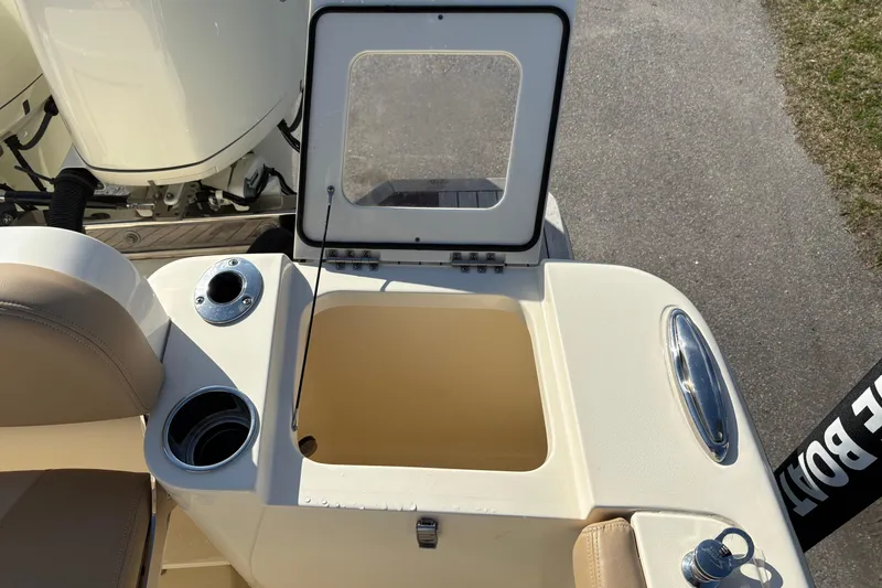 Slide: The Image of 2023 Scout 277 LXF boat storage compartment with open lid and cup holders. - 10