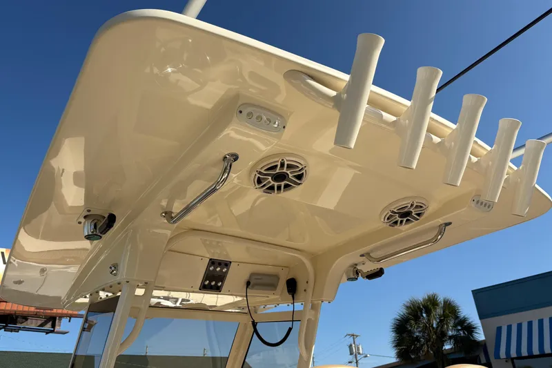 Slide: The Image of 2023 Scout 277 LXF boat roof with rod holders and speakers under clear blue sky. - 18