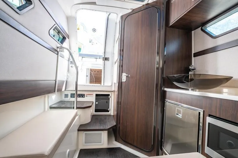 Slide: The Image of Interior of 2025 Edgewater 370CC boat with modern wood finishes and compact amenities. - 13