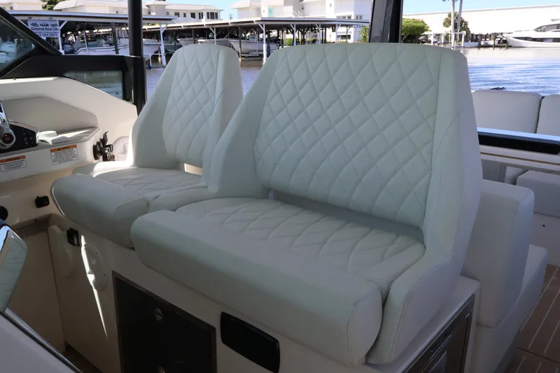 Slide: The Image of Two cushioned seats with diamond stitching in a modern boat cockpit, surrounded by water and buildings. - 35