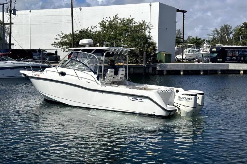 Slide: The Image of 2006 Boston Whaler 285 Conquest boat with Suzuki engines in a marina setting. - 19