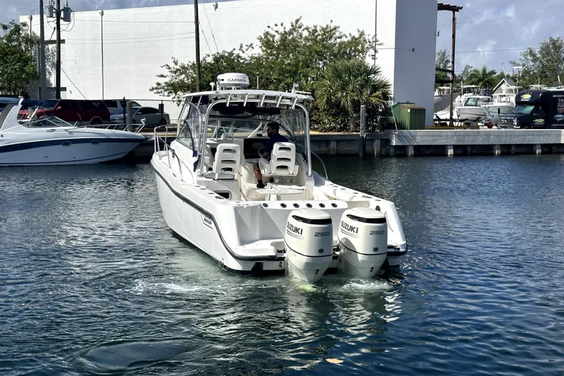 Slide: The Image of 2006 Boston Whaler 285 Conquest boat with twin Suzuki engines in a marina. - 24