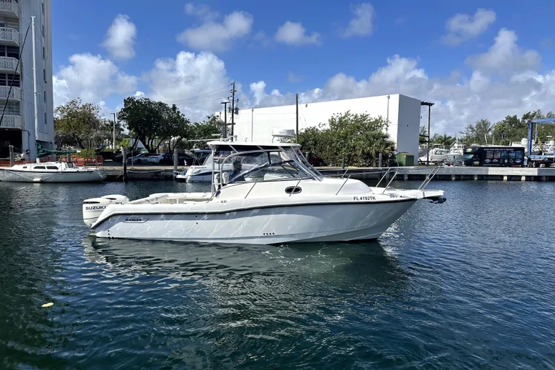 Slide: The Image of 2006 Boston Whaler 285 Conquest boat docked in a marina under a clear blue sky. - 26