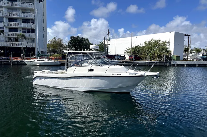 Slide: The Image of 2006 Boston Whaler 285 Conquest boat docked in a marina under a clear blue sky. - 27