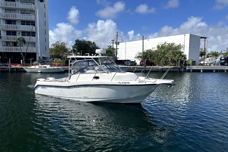 Slide: The Image of 2006 Boston Whaler 285 Conquest boat docked in a marina under a clear blue sky. - 28