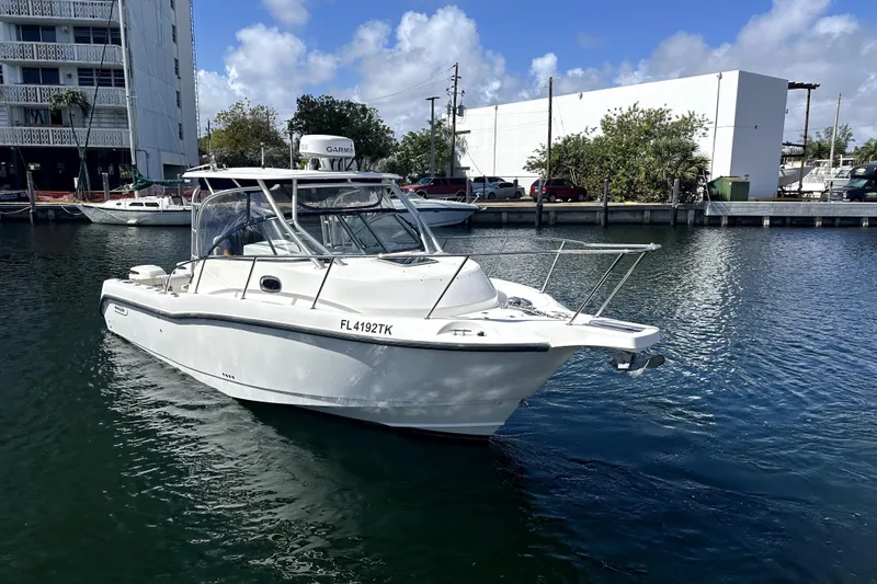 Slide: The Image of 2006 Boston Whaler 285 Conquest boat on calm water near a marina. - 32