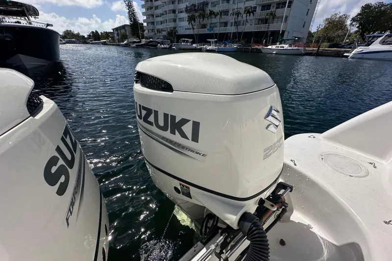 Slide: The Image of Twin Suzuki outboard engines on a 2006 Boston Whaler 285 Conquest, docked by waterfront buildings. - 43