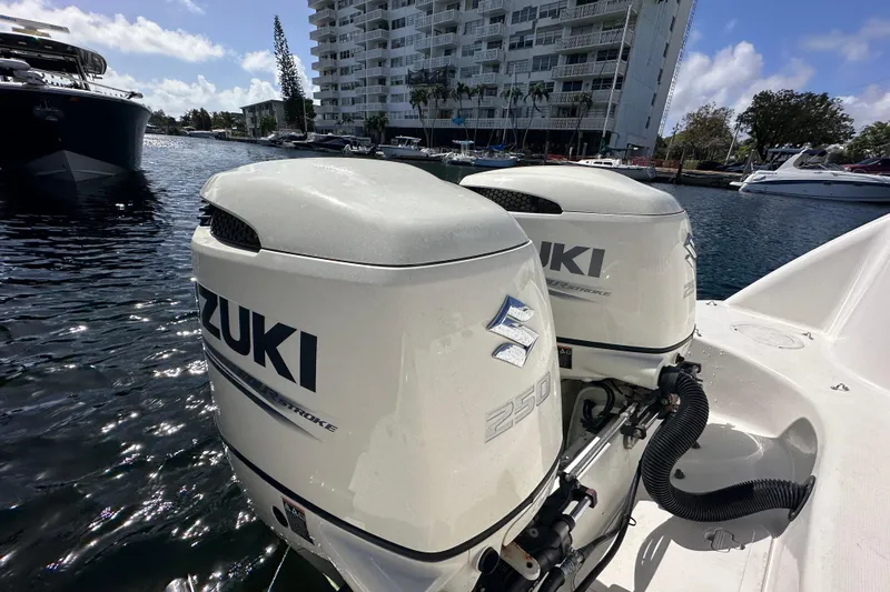 Slide: The Image of Twin Suzuki outboard engines on a 2006 Boston Whaler 285 Conquest, docked near waterfront buildings. - 44