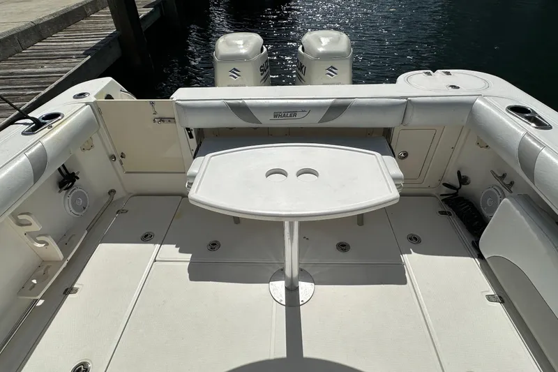 Slide: The Image of 2006 Boston Whaler 285 Conquest boat interior with seating and table, docked by water. - 48