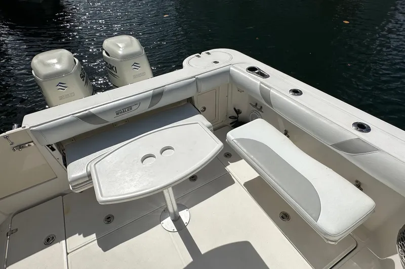 Slide: The Image of 2006 Boston Whaler 285 Conquest boat interior with seating and table, featuring Suzuki engines. - 49