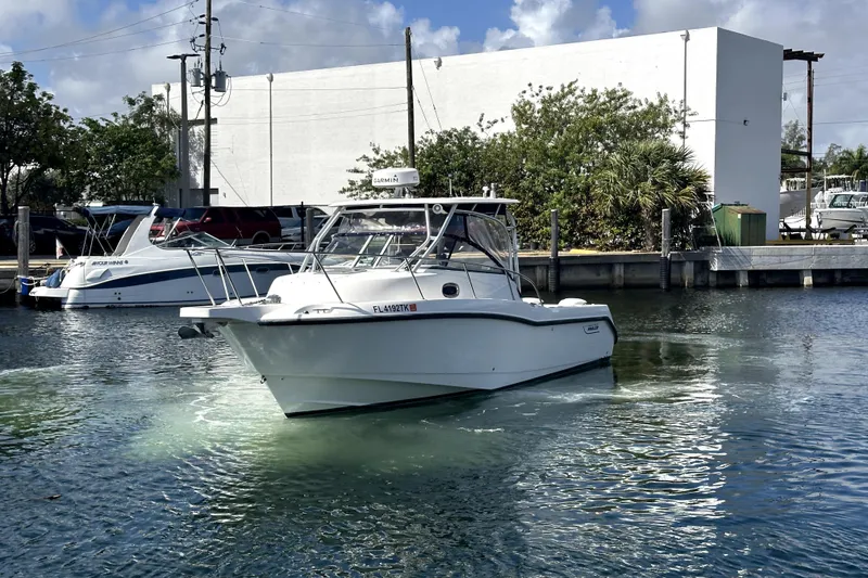 Slide: The Image of 2006 Boston Whaler 285 Conquest boat docked in a marina under a clear sky. - 5