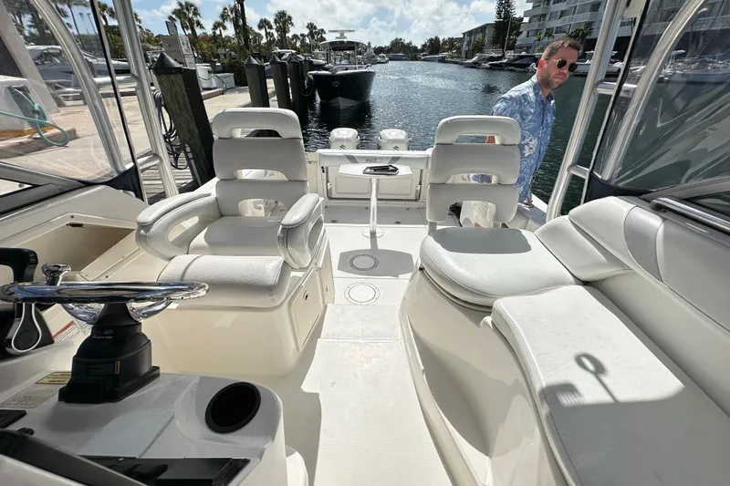 Slide: The Image of 2006 Boston Whaler 285 Conquest interior with white seating and steering wheel, docked by water. - 71