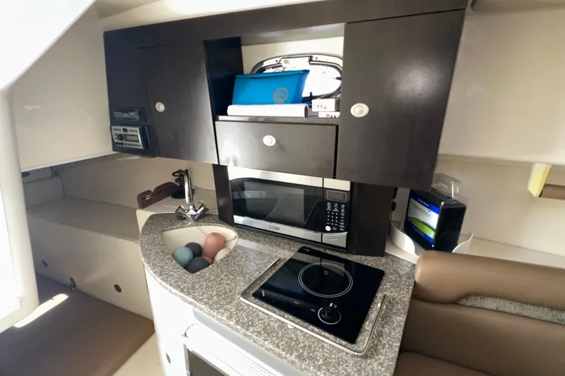 Slide: The Image of 2006 Boston Whaler 285 Conquest cabin kitchen with microwave, stove, and storage cabinets. - 76