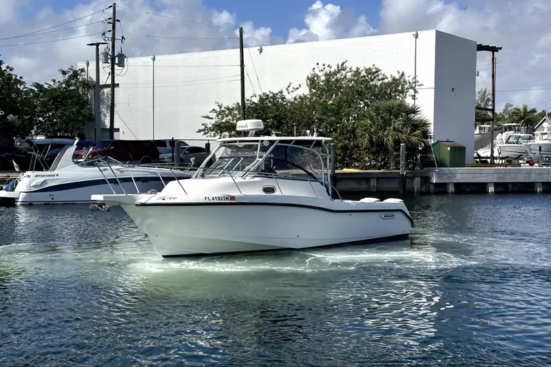 Slide: The Image of 2006 Boston Whaler 285 Conquest boat docked in a marina under a clear sky. - 8
