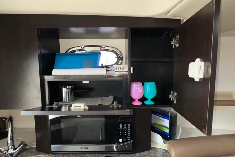 Slide: The Image of 2006 Boston Whaler 285 Conquest interior with microwave, colorful cups, and storage cabinets. - 82