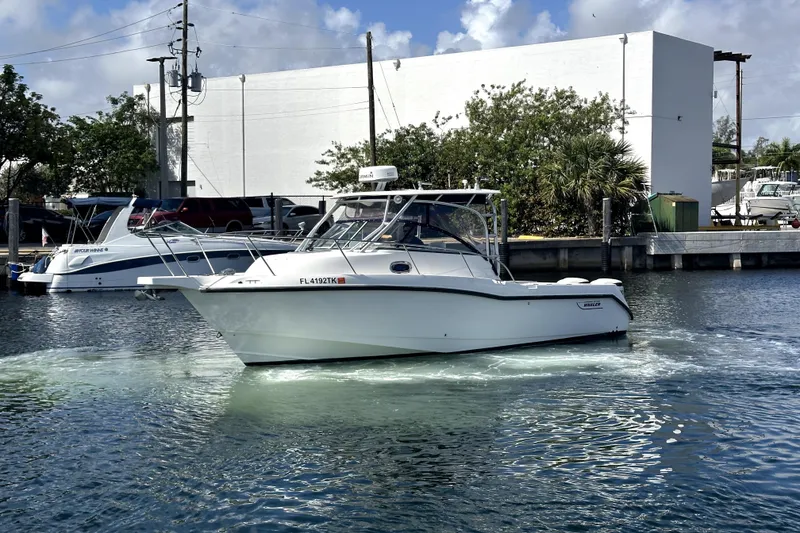 Slide: The Image of 2006 Boston Whaler 285 Conquest boat docked in a marina under a clear sky. - 9