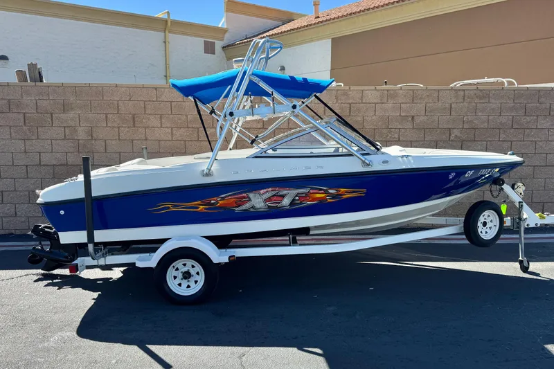 The Image of 2006 Bayliner 175 XT boat with blue hull and trailer, parked outdoors. - 0