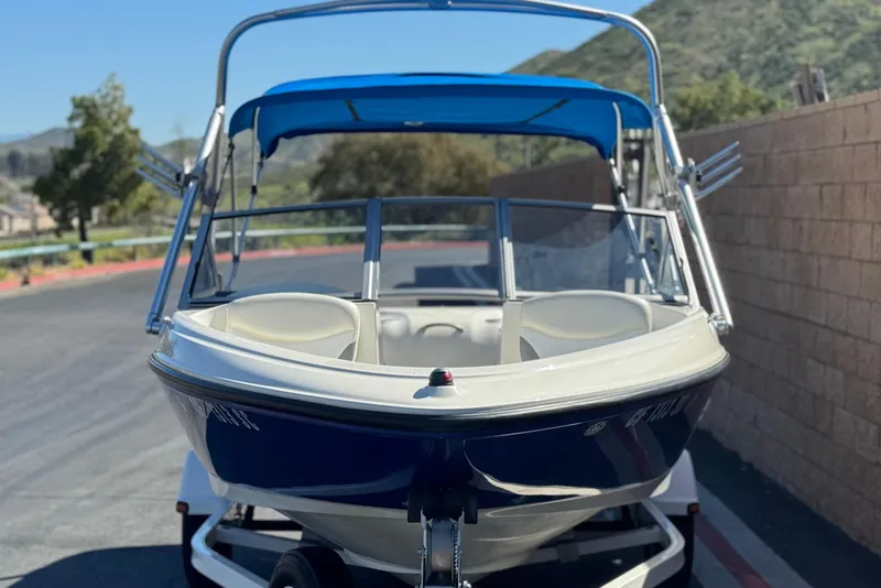 Slide: The Image of 2006 Bayliner 175 XT boat with blue canopy on a trailer, parked outdoors. - 2