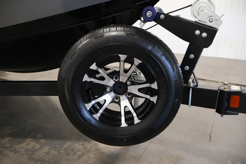 Slide: The Image of 2024 Lowe Fishing Machine 1775WT trailer wheel, black and silver design, on concrete floor. - 45