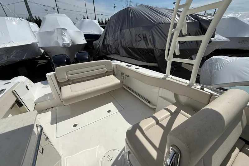 Slide: The Image of 2016 Boston Whaler 270 Vantage boat interior with seating, docked among covered boats. - 38