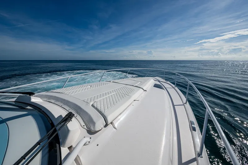 Slide: The Image of 2023 Intrepid 477 Evolution yacht cruising on open sea under clear blue sky. - 12