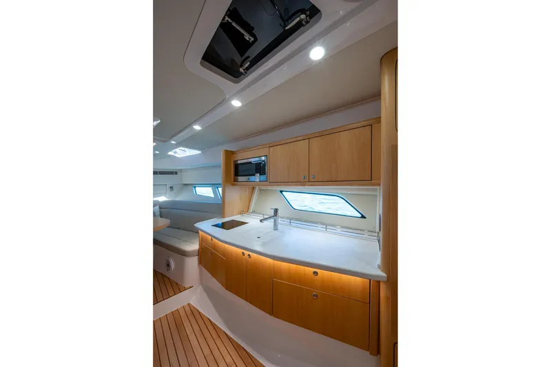 Slide: The Image of 2023 Intrepid 477 Evolution yacht interior with modern kitchen and wooden cabinetry. - 21