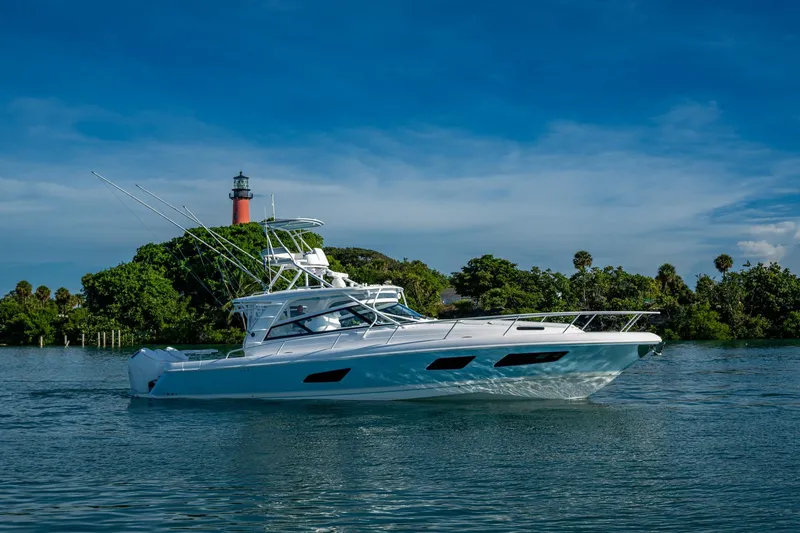 Slide: The Image of 2023 Intrepid 477 Evolution yacht cruising near a lighthouse and lush greenery. - 69