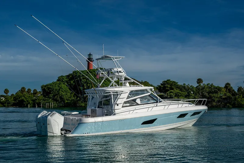 Slide: The Image of 2023 Intrepid 477 Evolution boat cruising near a lighthouse, surrounded by lush greenery. - 72