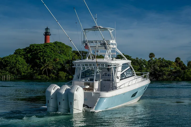 Slide: The Image of 2023 Intrepid 477 Evolution boat cruising near a lighthouse, surrounded by lush greenery. - 74