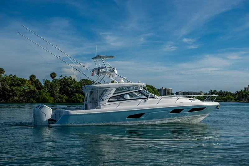Slide: The Image of 2023 Intrepid 477 Evolution boat cruising on a serene waterway under a clear blue sky. - 86
