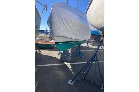 Slide: The Image of 1984 BHM CC Flye Point Launch boat covered and elevated on stands in a marina. - 5