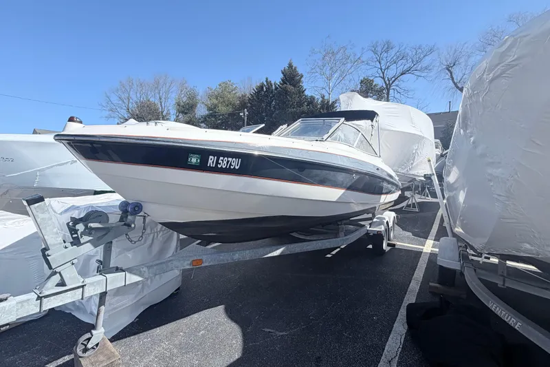 The Image of 2007 Bayliner 225 boat on trailer, parked outdoors under clear blue sky. - 1