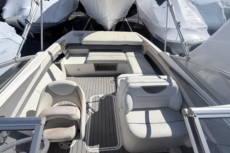 Slide: The Image of 2007 Bayliner 225 boat interior with white seating and deck, surrounded by covered boats. - 3