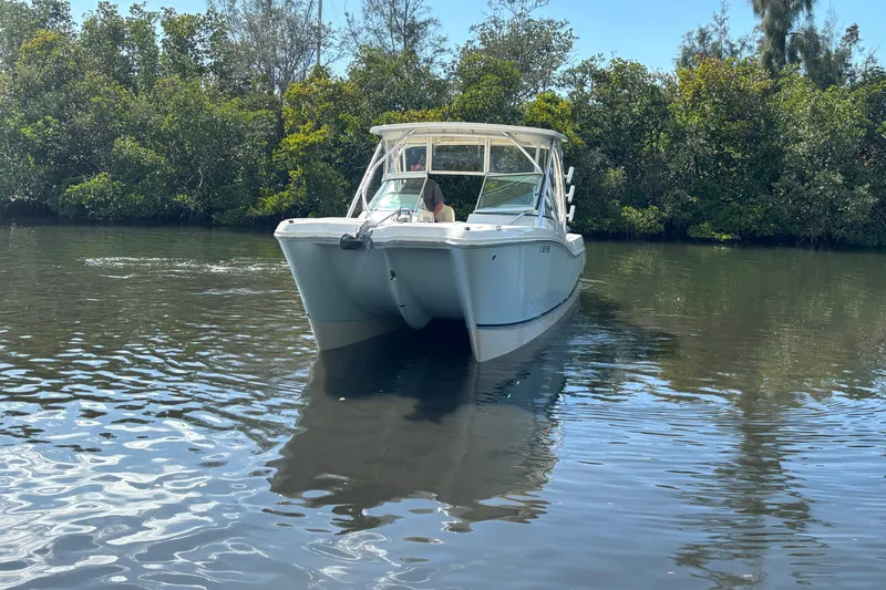 Slide: The Image of 2013 World Cat 290 DC boat cruising on a calm river with lush greenery. - 3