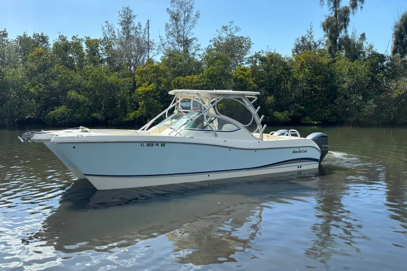 Slide: The Image of 2013 World Cat 290 DC boat cruising on calm water near lush greenery. - 5