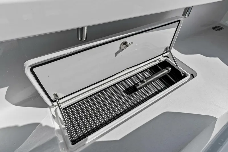 Slide: The Image of 2024 Custom Center Console High Ground Boatworks storage compartment with secure latch and interior mat. - 31