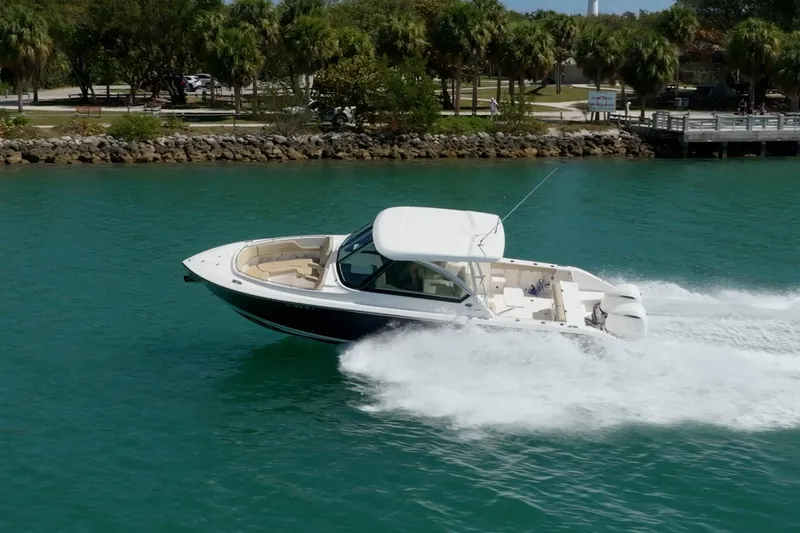 Slide: The Image of 2017 Pursuit DC 325 Dual Console boat cruising on turquoise water near a lush shoreline. - 20
