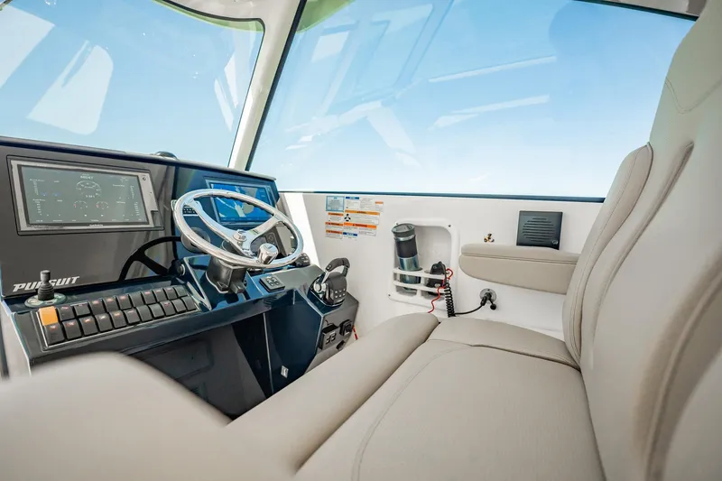 Slide: The Image of Interior view of 2017 Pursuit DC 325 Dual Console boat cockpit with steering wheel and controls. - 25