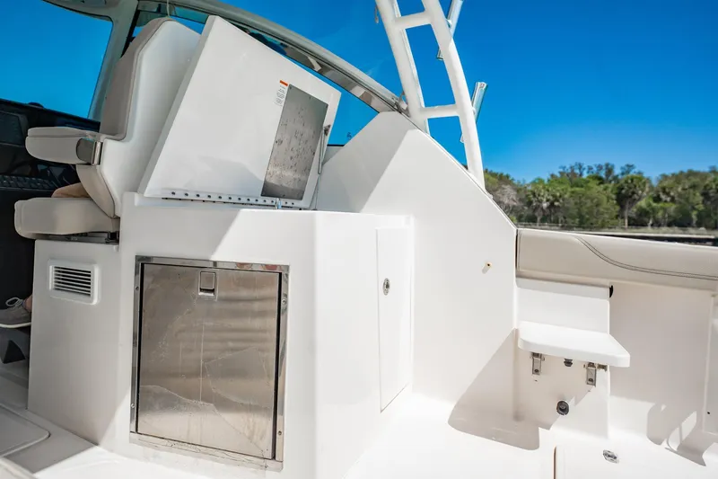 Slide: The Image of 2017 Pursuit DC 325 Dual Console boat interior with seating and storage, under clear blue sky. - 39