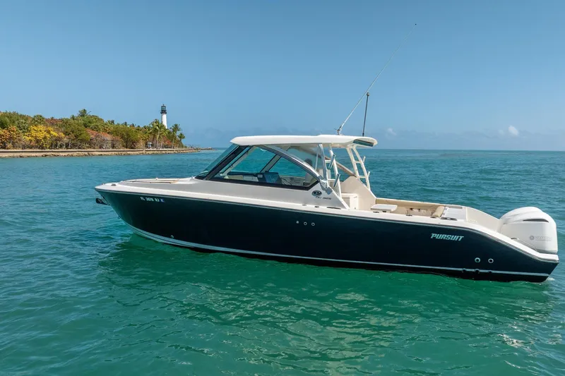 Slide: The Image of 2017 Pursuit DC 325 Dual Console boat on clear blue water near a lighthouse. - 54