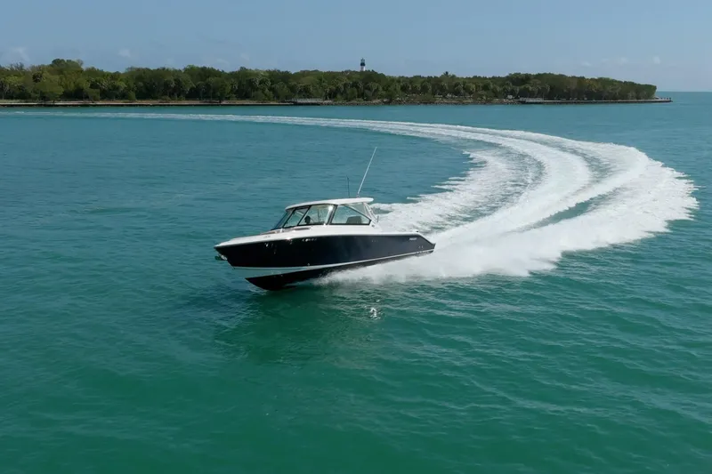 Slide: The Image of 2017 Pursuit DC 325 Dual Console boat cruising on clear blue water near a lush island. - 64