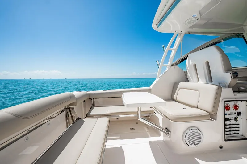 Slide: The Image of 2017 Pursuit DC 325 Dual Console boat interior with ocean view, featuring comfortable seating and table. - 80