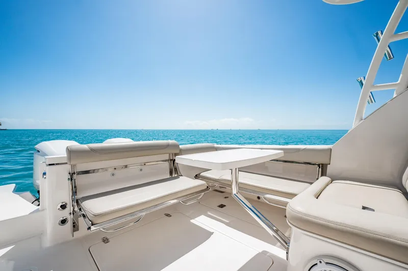 Slide: The Image of 2017 Pursuit DC 325 Dual Console boat interior with ocean view, featuring seating and table. - 81