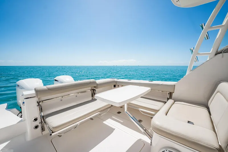 Slide: The Image of 2017 Pursuit DC 325 Dual Console boat interior with ocean view, featuring comfortable seating and table. - 82