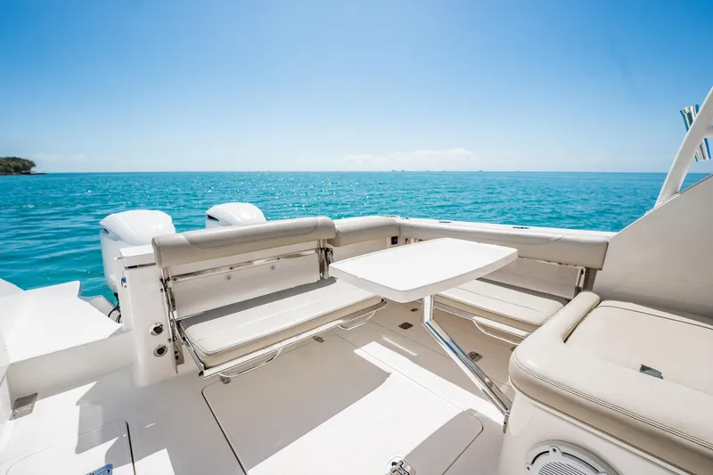 Slide: The Image of 2017 Pursuit DC 325 Dual Console boat interior with ocean view, featuring seating and table. - 83
