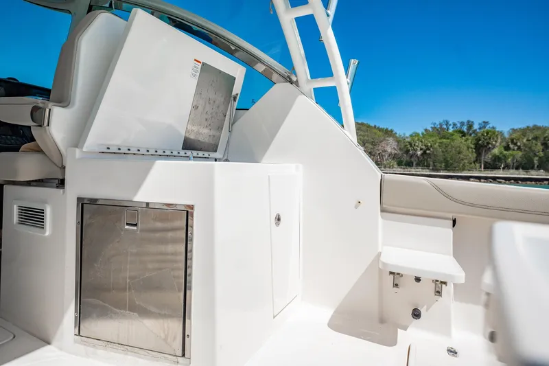 Slide: The Image of 2017 Pursuit DC 325 Dual Console boat interior with storage and seating, under clear blue sky. - 84