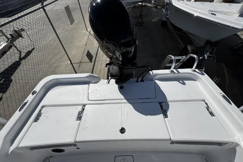 Slide: The Image of 2026 Blazer PureBay 2200 boat with outboard motor, docked near other vessels. - 24