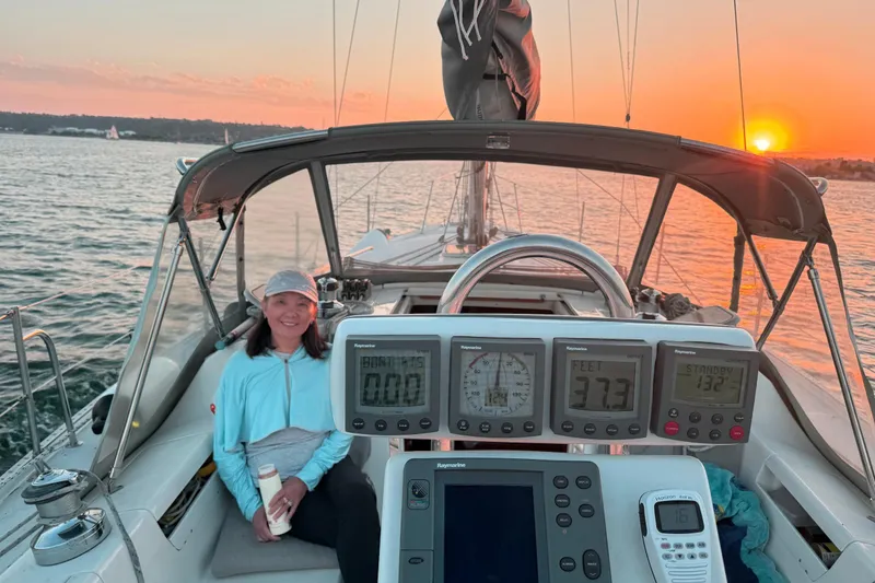 The Image of Woman enjoying sunset on a 2003 Catalina 34 MkII sailboat, with navigation instruments visible. - 0