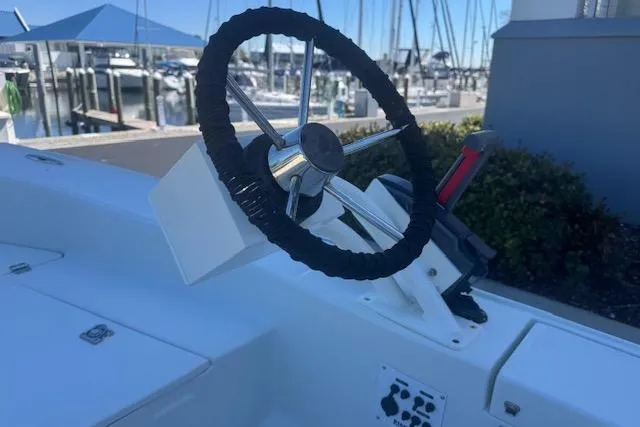 Slide: The Image of Steering wheel of 2024 Rigid Boats 10 Sport at marina, showcasing sleek design. - 11