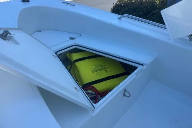 Slide: The Image of 2024 Rigid Boats 10 Sport with open storage compartment, featuring a yellow safety bag. - 12